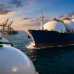 Ammonia tanker ship near industrial port with storage tanks during sunset