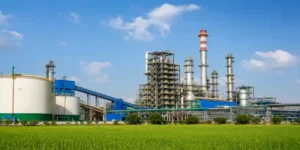 Large fertilizer and chemical manufacturing plant surrounded by green agricultural fields under a clear blue sky.