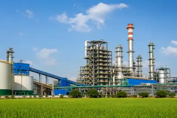 Large fertilizer and chemical manufacturing plant surrounded by green agricultural fields under a clear blue sky.